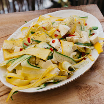 Frischer Zucchinisalat mit gelben und grünen Zucchinistreifen, Mozzarella und Chili